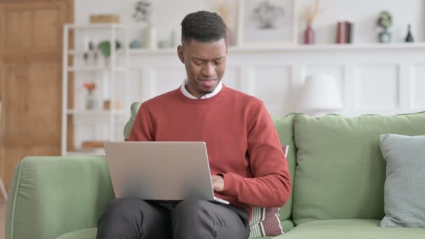 Afričan muž s notebookem s bolestí zápěstí na pohovce — Stock video