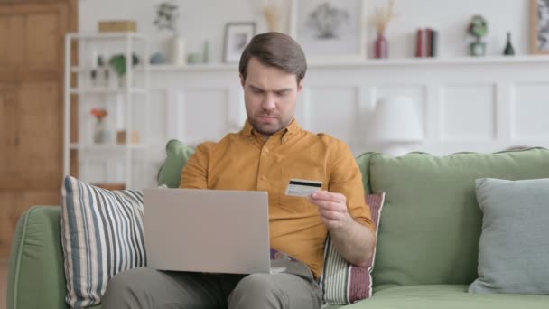 Homem novo com pagamento em linha mal sucedido no portátil no sofá — Vídeo de Stock
