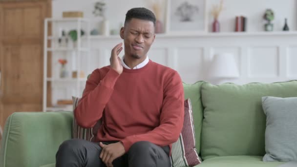 Afrikaanse man met nekpijn terwijl hij op de bank zit — Stockvideo