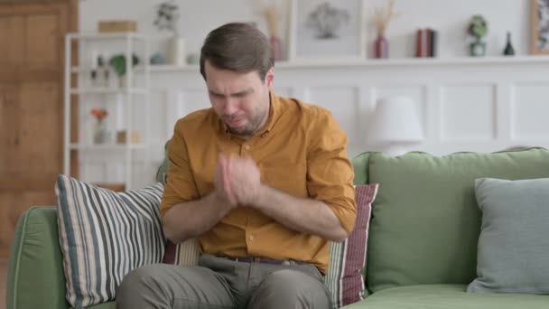 Junger Mann hustet im Sitzen auf Sofa — Stockvideo