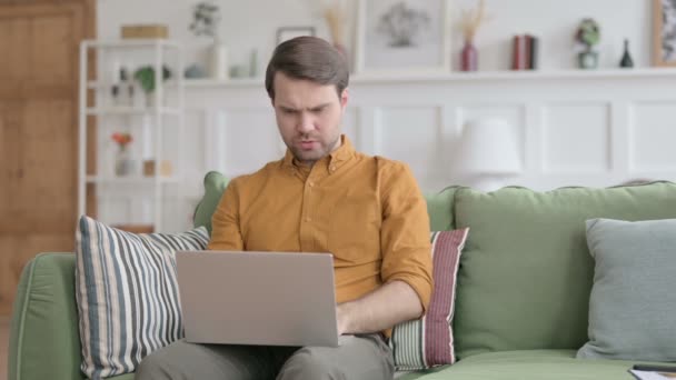 Dizüstü bilgisayarlı genç adam kanepeye öksürüyor. — Stok video