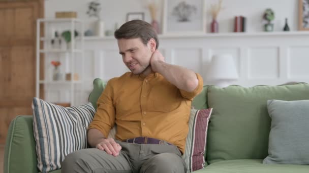 Jeune homme ayant mal au cou tout en étant assis sur le canapé — Video
