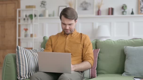 Mladý muž dělá video hovor na notebooku na pohovce — Stock video