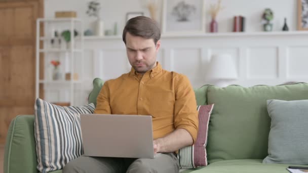 Mladý muž s notebookem s bolestí hlavy na pohovce — Stock video