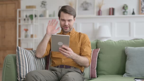 Jeune homme parlant sur vidéo appel sur tablette sur canapé — Video