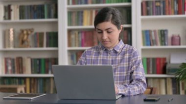 Ofiste dizüstü bilgisayar kullanırken kameraya gülümseyen Hintli kadın