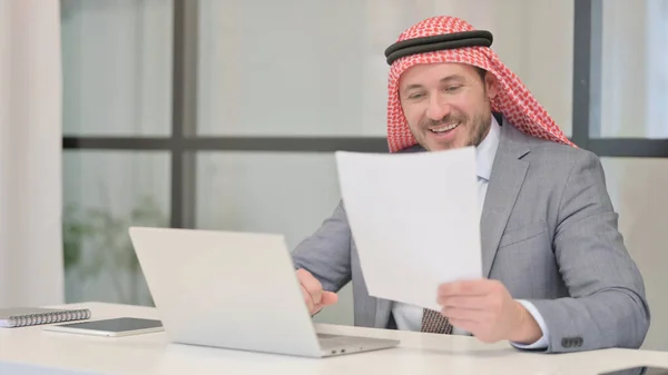 拥有笔记本电脑阅读文档的阿拉伯商人 — 图库照片