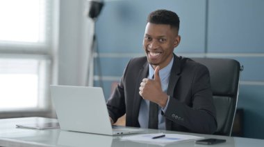 Ofiste dizüstü bilgisayar kullanırken Afrikalı İşadamı İşaretini Gösteriyor