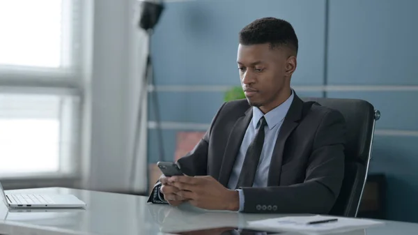 Afrikanischer Geschäftsmann mit Smartphone im Büro — Stockfoto