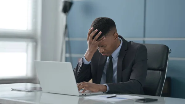 Un om de afaceri african are dureri de cap în timp ce lucrează la laptop — Fotografie, imagine de stoc