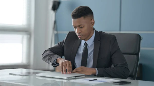 Afrikanischer Geschäftsmann kommt zurück und öffnet Laptop im Büro — Stockfoto