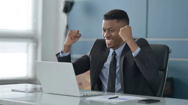 Afrikanischer Geschäftsmann feiert Erfolg mit Laptop im Büro — Stockfoto