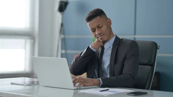 Afrikansk affärsman med nacksmärta när du använder laptop i Office — Stockfoto