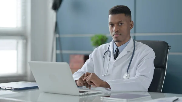 Afrikanska läkare tittar på kameran när du använder laptop i Office — Stockfoto