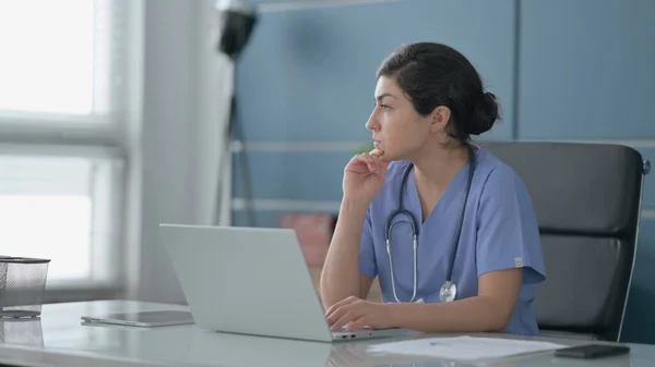 Indiase vrouwelijke arts denken tijdens het werken op laptop in Office — Stockfoto