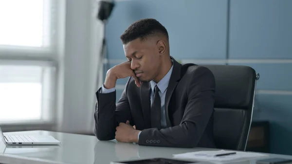 Un om de afaceri african supărat se simte îngrijorat în timp ce stă la birou — Fotografie, imagine de stoc