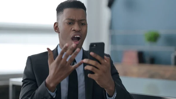 Portrét afrického podnikatele reagujícího na ztrátu na chytrém telefonu — Stock fotografie