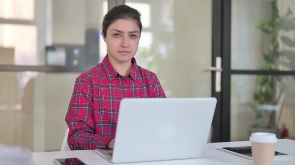 Indiase vrouw op zoek naar camera tijdens het gebruik van laptop — Stockfoto