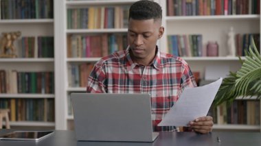 Dizüstü bilgisayarlı Afrikalı Ofiste Belgeler Okuyor 