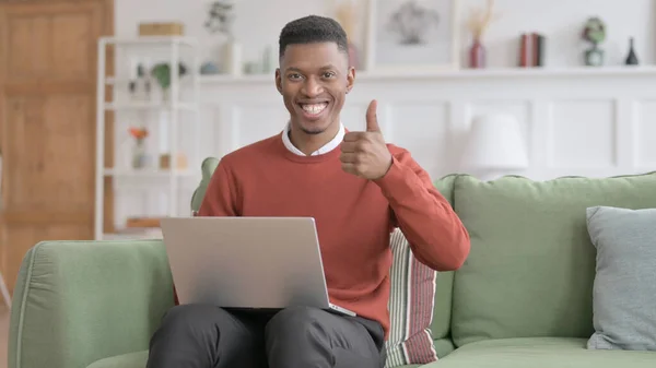 African Man visar tummen upp Logga in När du använder laptop på soffan — Stockfoto