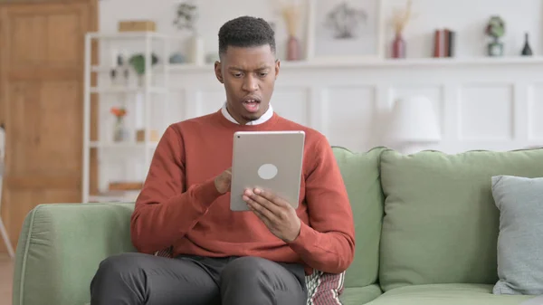 Homem africano ter perda no tablet no sofá — Fotografia de Stock