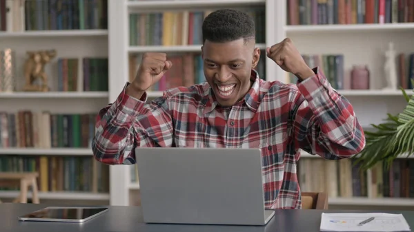Afrikai Man Ünnepelje siker használata közben Laptop az irodában — Stock Fotó