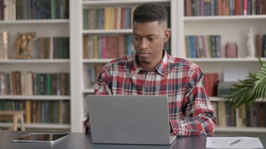 Ofisteki dizüstü bilgisayarda çalışan Afrikalı Adam