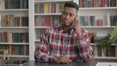 Ofiste akıllı telefondan konuşan Afrikalı adam. 