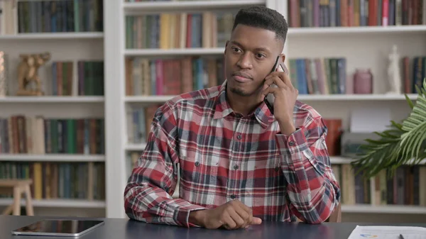 Ofiste akıllı telefondan konuşan Afrikalı adam. 