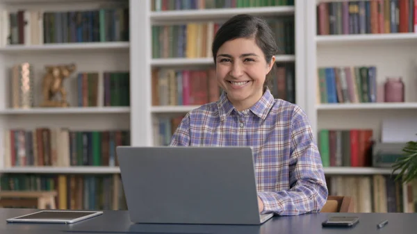 Ofiste dizüstü bilgisayar kullanırken kameraya gülümseyen Hintli kadın — Stok fotoğraf