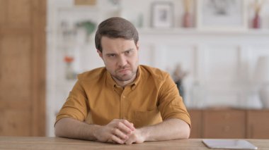 Ofiste otururken üzgün hisseden genç adam.