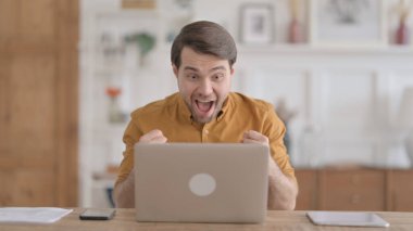 Ofiste dizüstü bilgisayar kullanırken Başarı Kutlaması Genç Adam