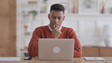 Ofisteki dizüstü bilgisayarda çalışırken düşünen Afrikalı adam
