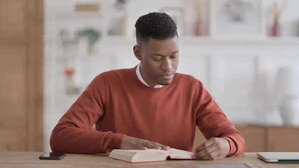 African Man Czytanie książki podczas siedzenia w biurze — Zdjęcie stockowe