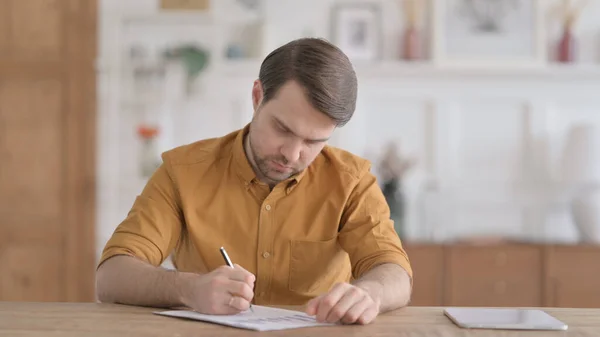 Jeune homme écrivant sur le papier au bureau — Photo