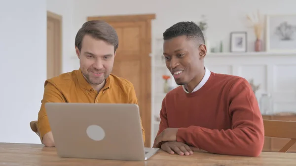 Homme africain et jeune homme discutant du travail sur ordinateur portable — Photo