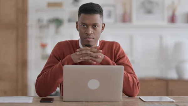 African Man Looking at Camera while using Laptop in Office — Fotografia de Stock