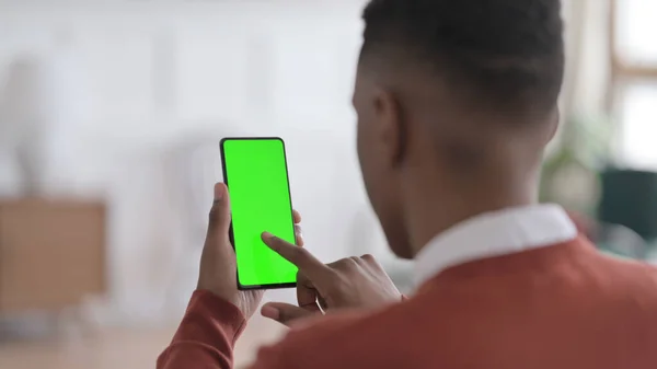 Zadní pohled na Afričana při pohledu na Smartphone se zelenou Chroma obrazovkou — Stock fotografie