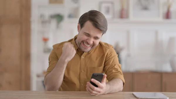 Úspěšný mladý muž slaví na smartphonu — Stock fotografie