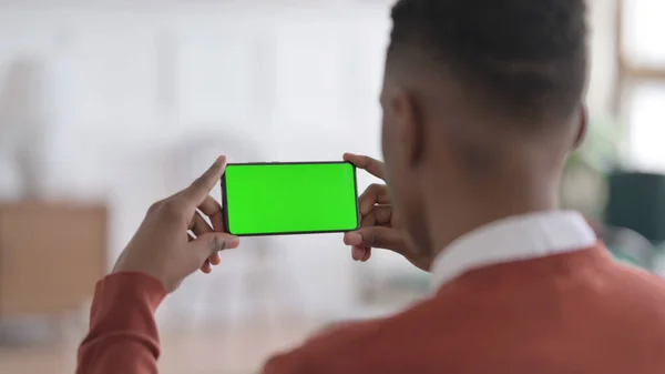 Zadní pohled na Afričana při pohledu na Smartphone se zelenou Chroma obrazovkou — Stock fotografie