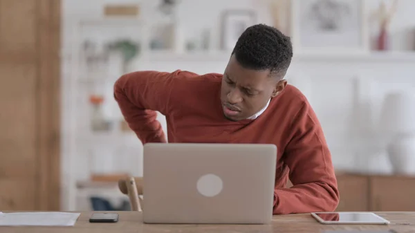사무실에서 노트북을 사용하면서 등의 통증을 겪고 있는 아프리카 남자 — 스톡 사진