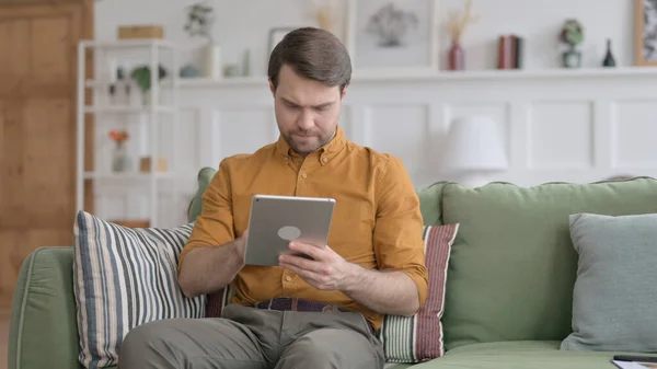 Junger Mann benutzt Tablet auf Sofa — Stockfoto