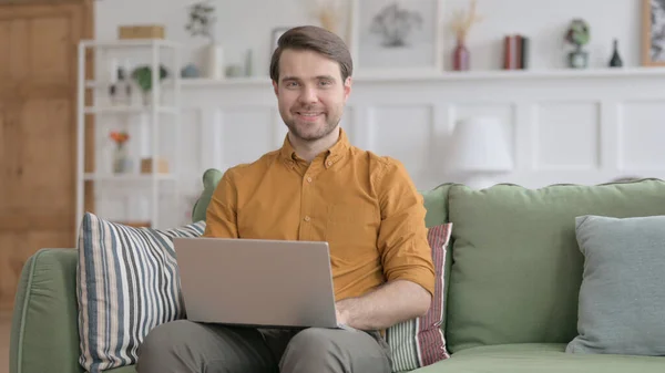 Unge mann smiler på kamera mens han bruker Laptop i kontoret – stockfoto