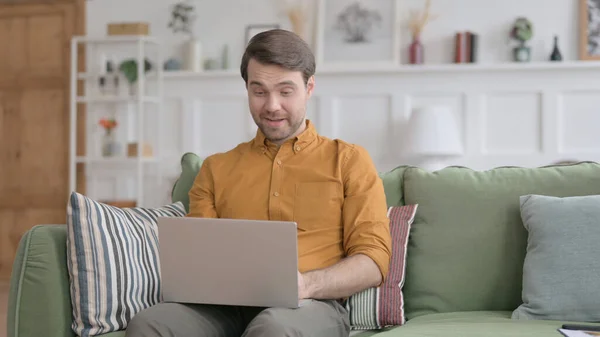 Mladý muž dělá video hovor na notebooku na pohovce — Stock fotografie