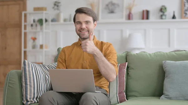 Jeune homme montrant pouce vers le haut signe tout en utilisant un ordinateur portable dans le bureau — Photo