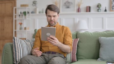 Video 'da konuşan genç adam Kanepede Tablet' i arıyor.