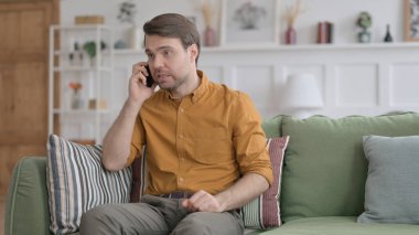 Kızgın genç adam telefonda konuşuyor.
