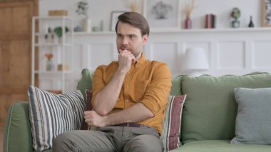 Genç adam koltukta otururken endişeli hissediyor.