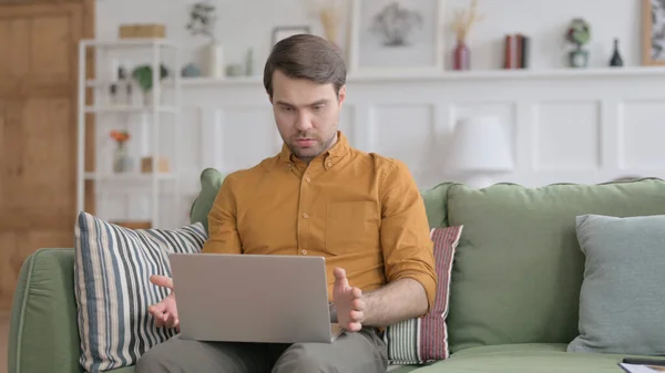 Junger Mann mit Laptop reagiert auf Verlust auf Sofa — Stockfoto