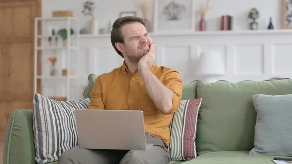 Junger Mann mit Laptop hat Nackenschmerzen auf Sofa — Stockfoto